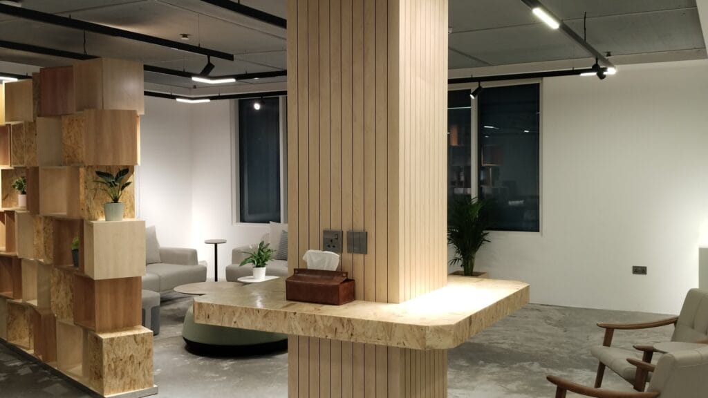 Corporate office reception lounge with wood slat feature column, built-in shelving and modern lighting, office interior fit-out in Business Bay, Dubai by Zale Interior