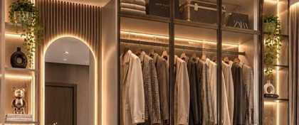 Custom walk-in wardrobe with hanging clothes and glass fronted cabinets, UAE
