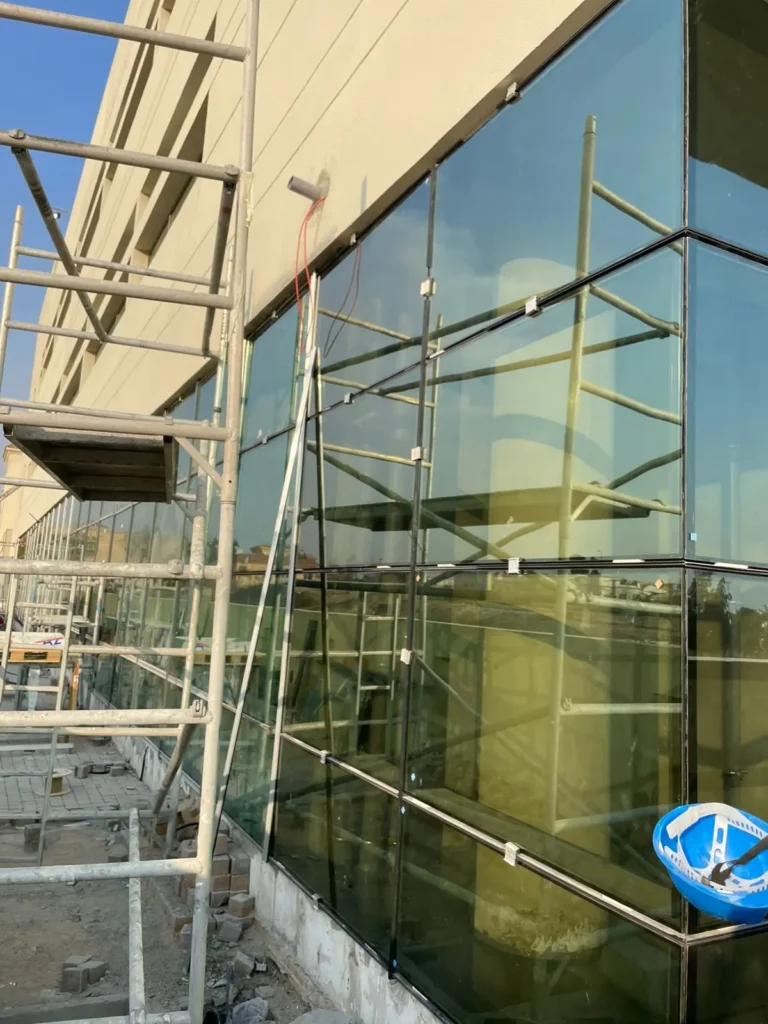Frameless glass facade panels being installed on a commercial building